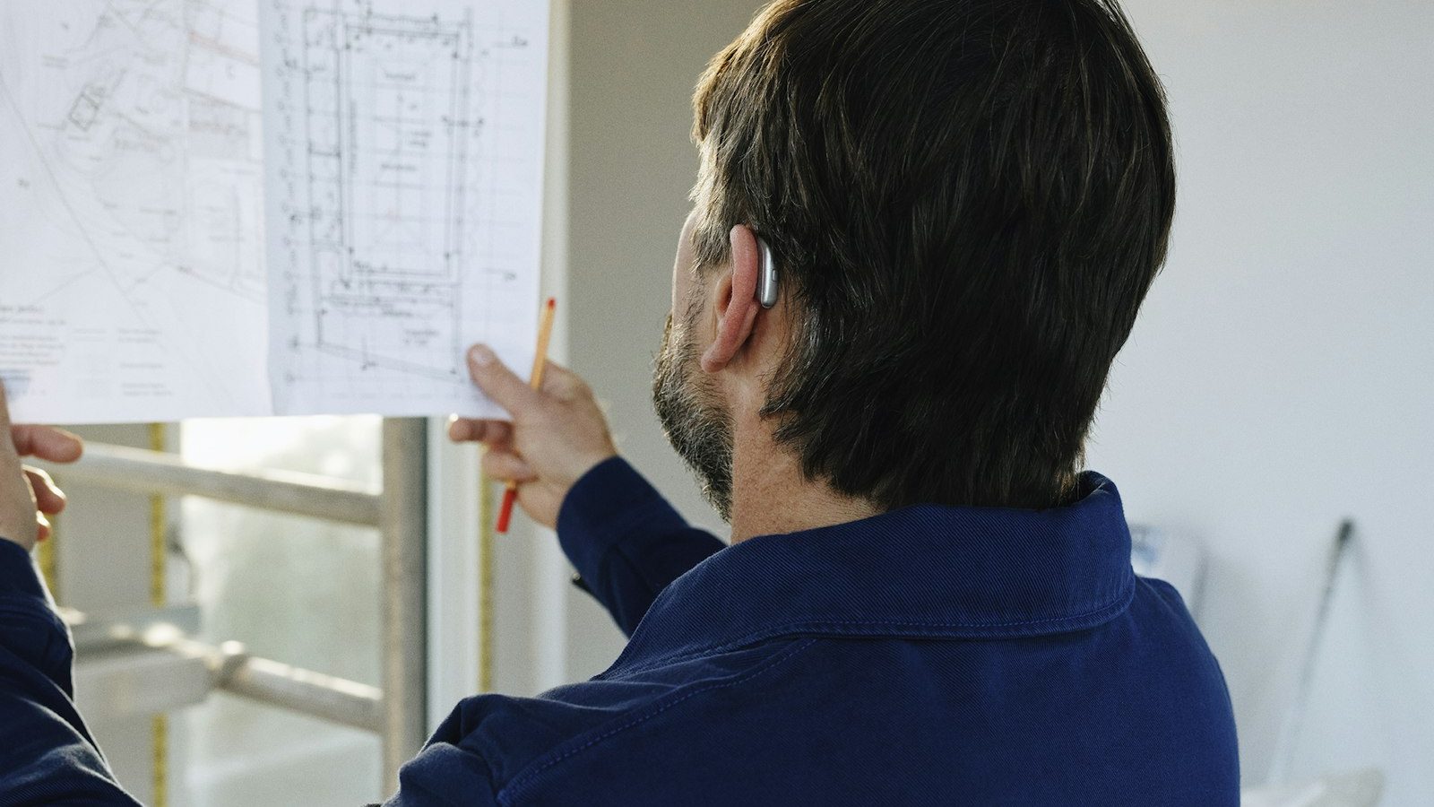 Contractor reviewing building plans inside an unfinished room