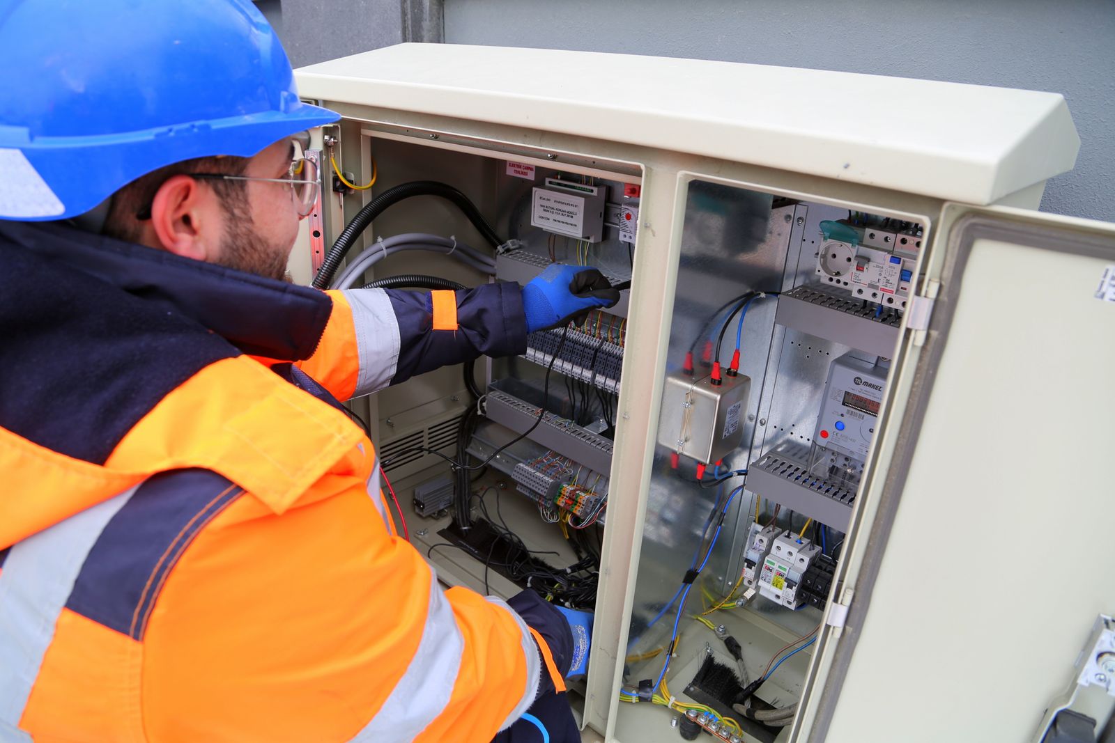 Electrician working on an industrial control cabinet with labelled modules