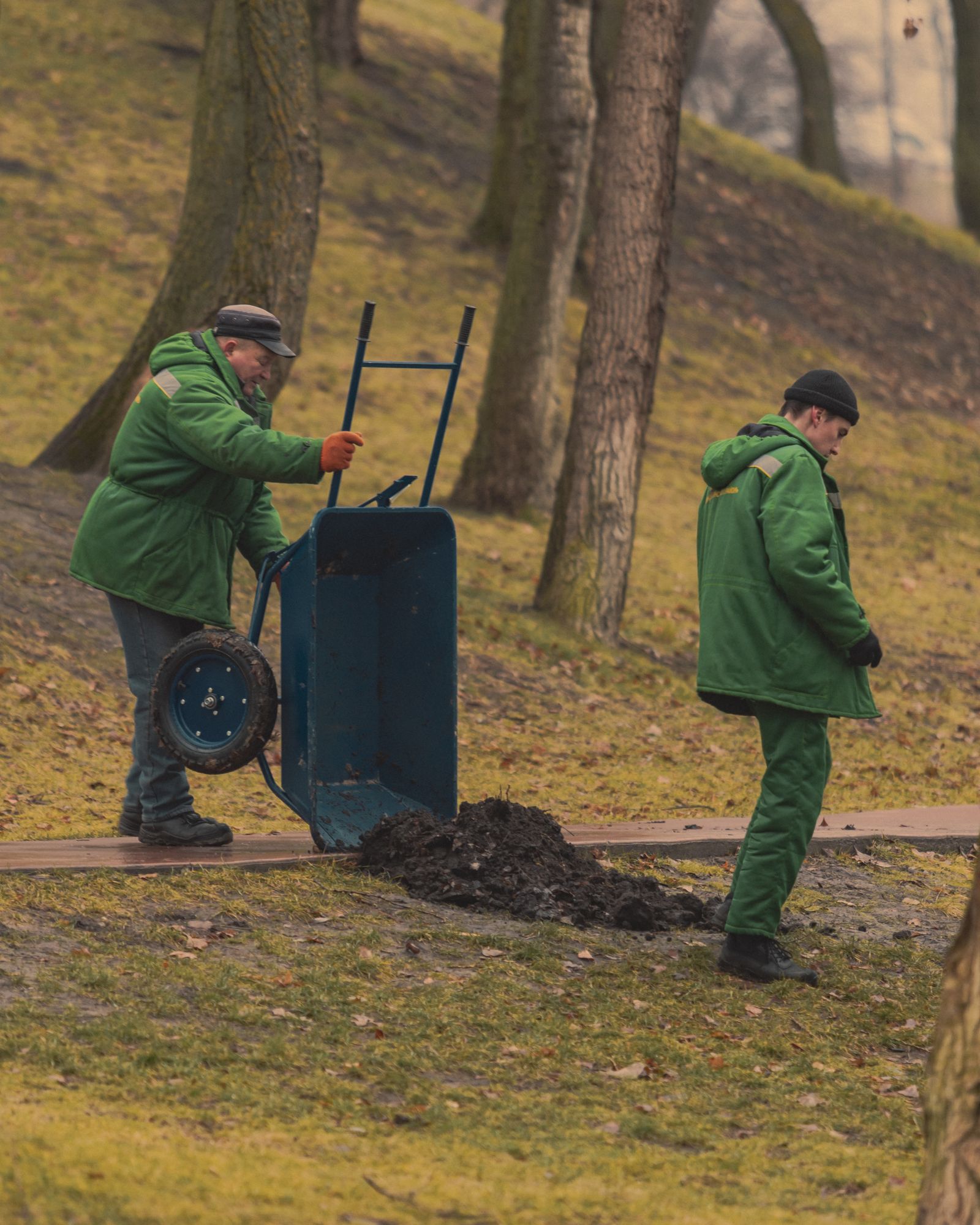 Grounds crew moving mulch and soil across a park landscape