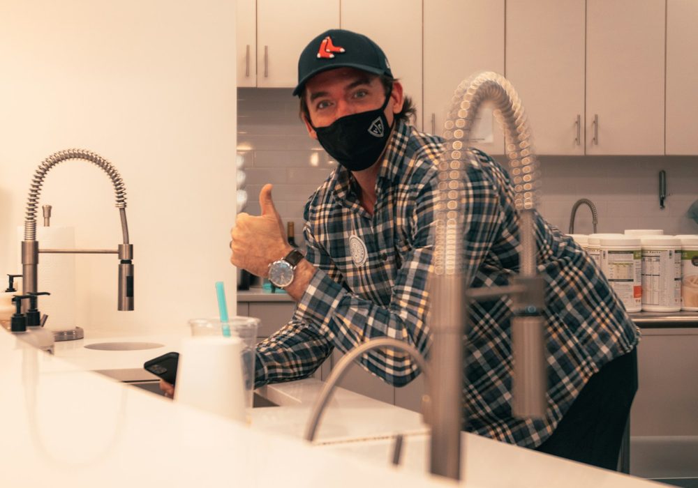Technician working at a kitchen sink with a tall gooseneck faucet